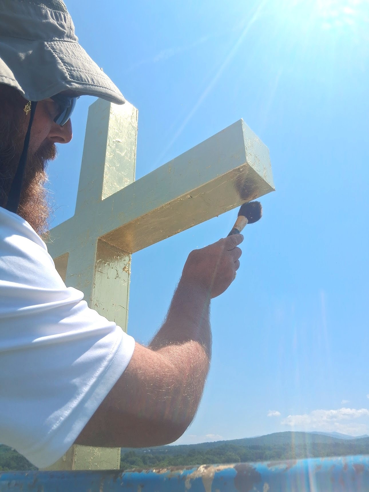 Craftsman applying gold leaf to cross with brush