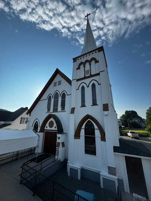 Elevated view of restored white church steeple with cross against blue sky, Woodsville, NH