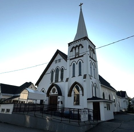 Restored white church with pointed steeple and cross at dusk, Woodsville, NH