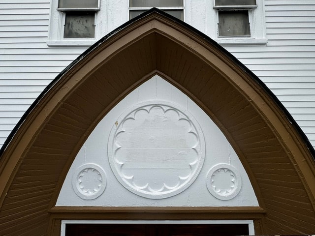 Close-up of decorative Gothic arch gable trim with rose window detail, Woodsville, NH — before